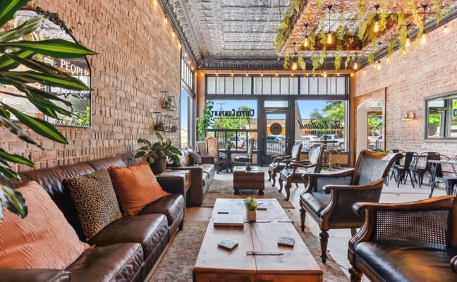 Swimming pool with brick patio surrounded by red brick building, wooden fence, lounge chairs, and covered seating area